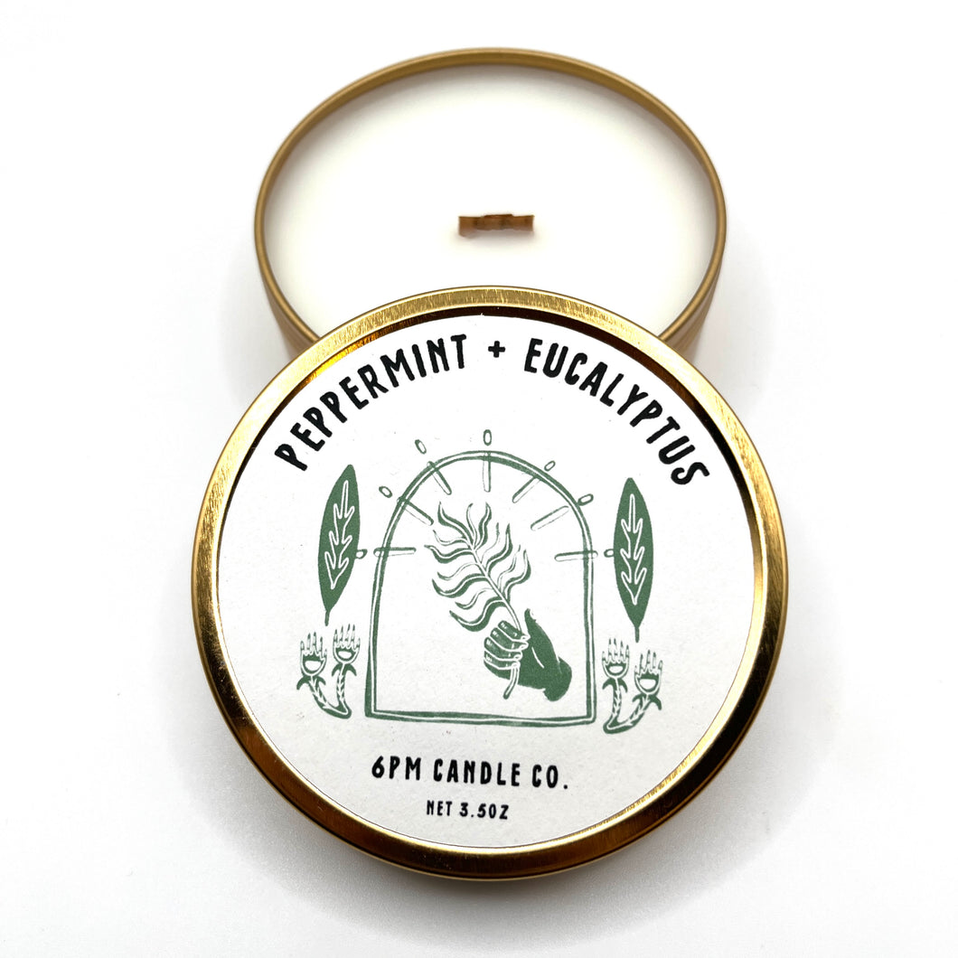 A travel-sized soy wax candle with a wooden wick, labelled '6pm Candle Co.', 'Peppermint + Eucalyptus'