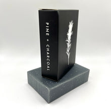 Load image into Gallery viewer, Bar soap with black packaging called 'Pine + Charcoal'
