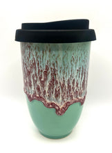 Load image into Gallery viewer, A ceramic travel mug with a black lid, featuring a swirled green and blue color pattern.
