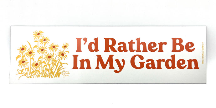 A rectangular white bumper sticker with the text 'I'd Rather Be In My Garden' and a floral design consisting of sunflowers.